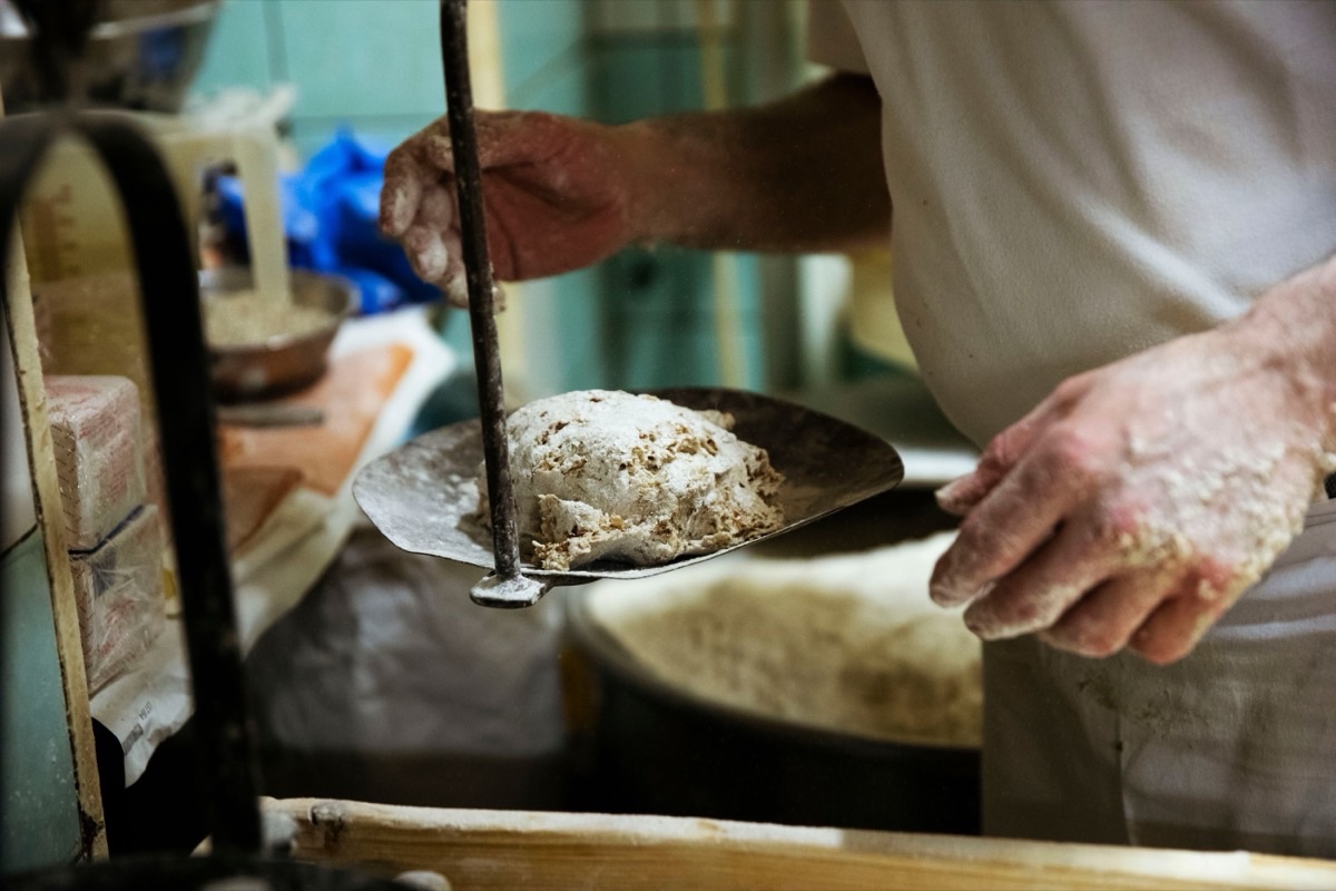 Bäcker schiebt Brot mit dem Holzschieber in den Ofen